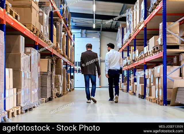 Businessman with colleague walking at warehouse