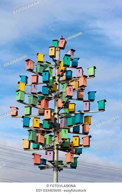 Colorful birdhouses on a background of blue sky with clouds