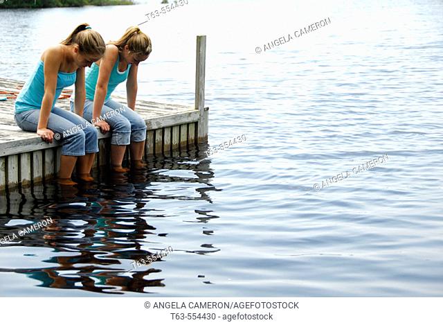 girl 13 girl 18 sitting on dock together looking at water