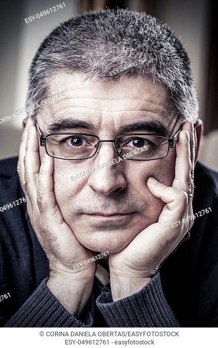 Portrait of mature adult Caucasian man with sorrow expression holding his face in his hands