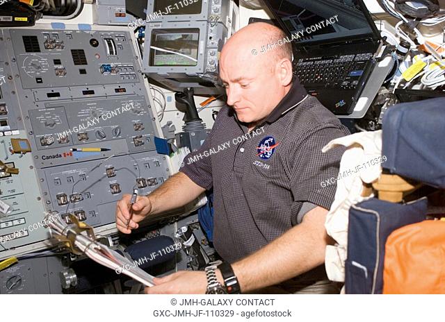 Astronaut Scott Kelly, STS-118 commander, looks over procedures checklists on the aft flight deck of Space Shuttle Endeavour while docked with the International...
