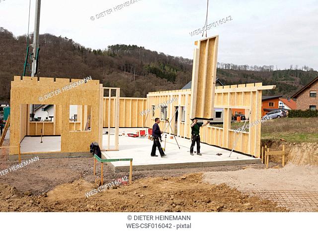 Europe, Germany, Rhineland Palantinate, Men installing and fixing wooden walls of prefabricated house