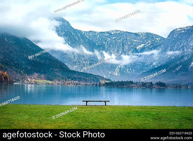 Beautiful scenery with the majestic Northern Limestone Alps, the Hallstatter lake and a wooden bench on its shore, in the famous Hallstatt town, in Austria