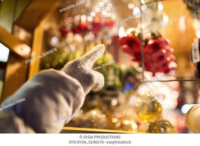 hand pointing at christmas toys behind shop window