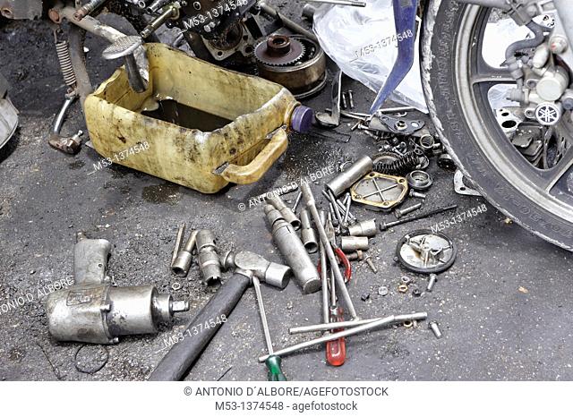 A dismantled Yamaha motorbike with engine parts and tools scattered on ground