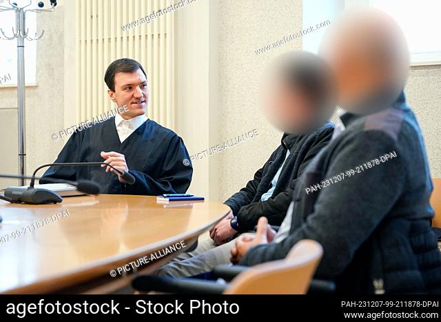 07 December 2023, Baden-Württemberg, Mannheim: Lawyer Timo van der Does (l) talks to the two defendants in the courtroom of the district court