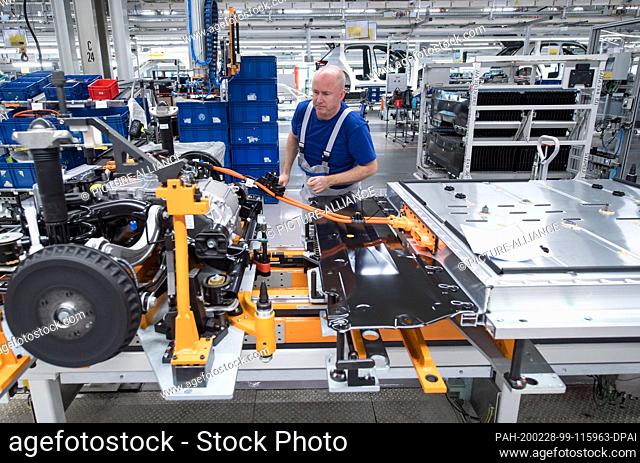 25 February 2020, Saxony, Zwickau: An employee of Volkswagen Sachsen in Zwickau wires the battery on a line for the new VW ID.3