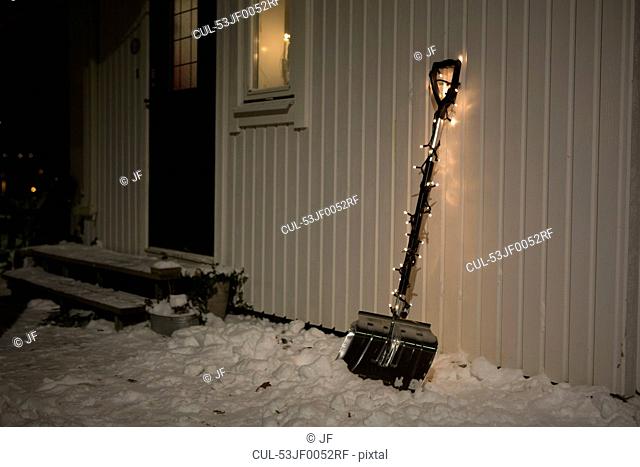 Shovel with fairy lights in snow