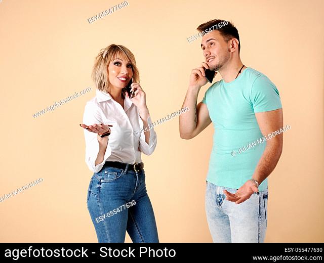 Two young people, man and woman, talking on mobile