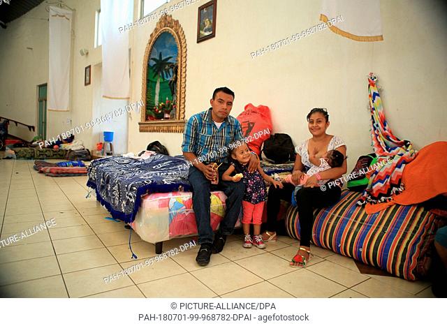 29 June 2018, Guatemala, Escuintla: Agricultural worker Julio Roberto Morenjon Lopez (23) sitting with his wife and two daughters in the emergency shelter at...