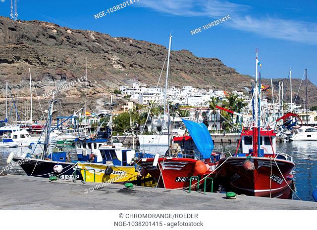 4 colorful fishing boats lying on the quay of the harbor of Puerto de Mogan