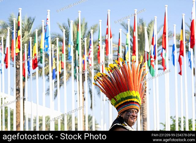 09 December 2023, United Arab Emirates, Dubai: A man with a headdress stands in front of flags on the COP28 grounds. The main topics of this year's UN Climate...
