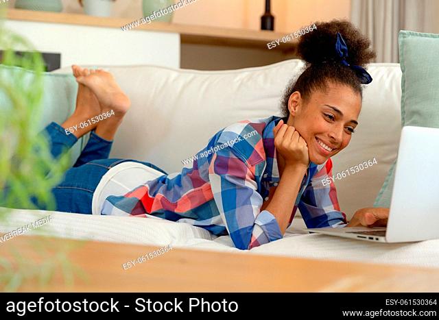 Mixed race woman sitting on couch using laptop at home