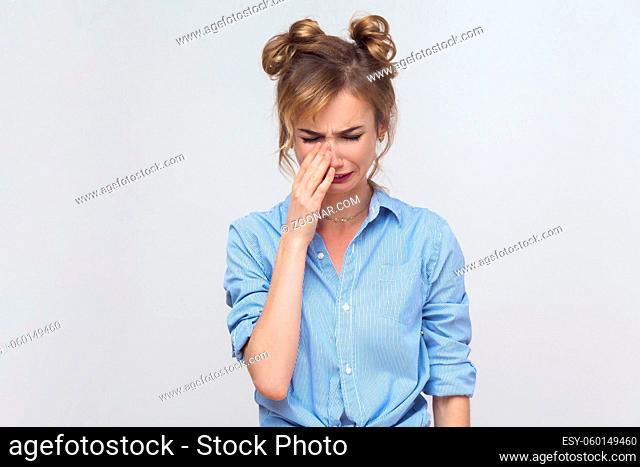 Depressed young caucasian woman, feeling ashamed or sick, covering face with both hands, keeping eyes closed. Human face expressions and emotions concept
