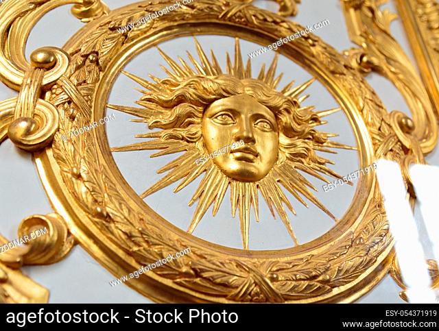 Detail view of golden ornate of Chateau de Versailles depicting human face. Paris, France, Europe