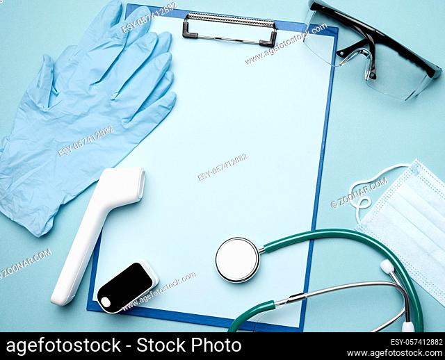 pulse oximeter and electronic thermometer and other medical supplies on a blue background, copy space, top view