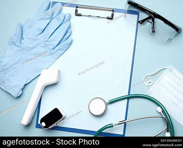 pulse oximeter and electronic thermometer and other medical supplies on a blue background, copy space, top view