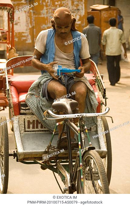 Rickshaw puller sitting on rickshaw, Chandni Chowk, Delhi, India