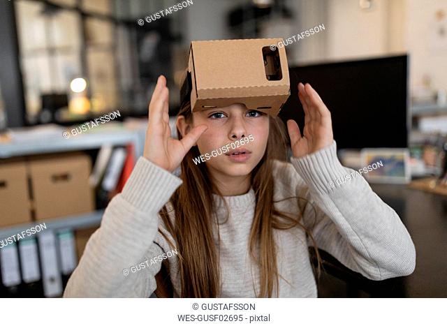 Girl with cardboard VR glasses in office