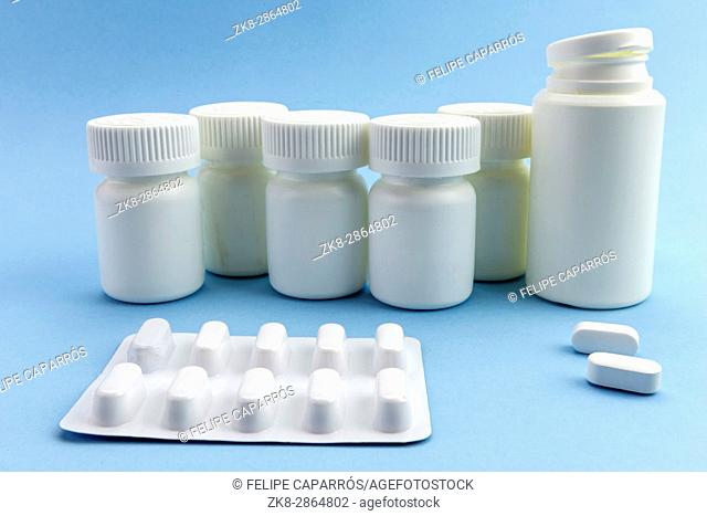 Pills pill bottles white with white tablets of different types on blue background