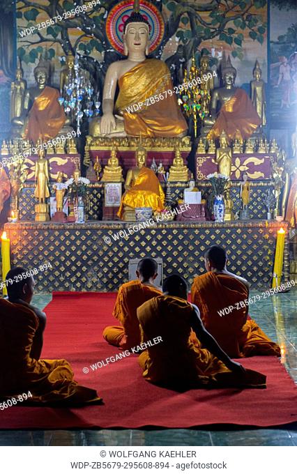 Monks are chanting and praying in the evening at Wat Prabat Tay (Wat Phra Bat Tai) in in the UNESCO world heritage town of Luang Prabang in Central Laos