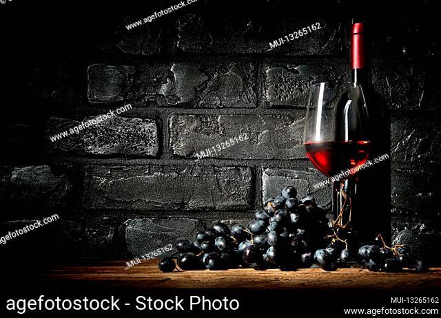 Bunch of grapes and wine on a black brick background