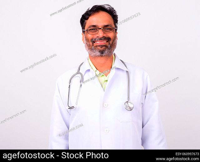 Studio shot of mature handsome bearded Indian man doctor against white background