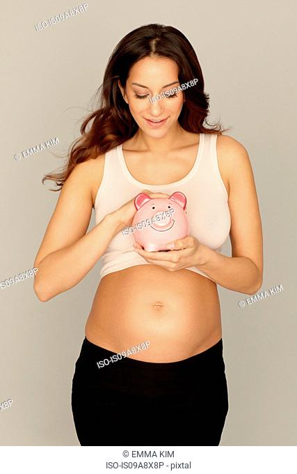 Pregnant woman holding piggy bank