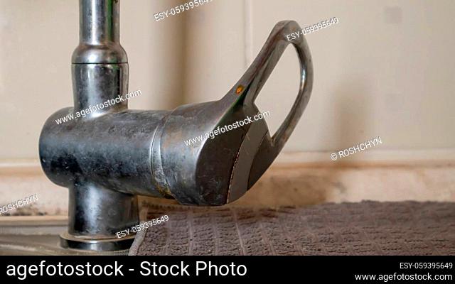 An old single lever valve with a leak. Chrome-plated basin mixer with running water on the basin