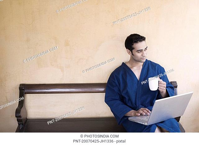 Young man sitting on a bench and using a laptop