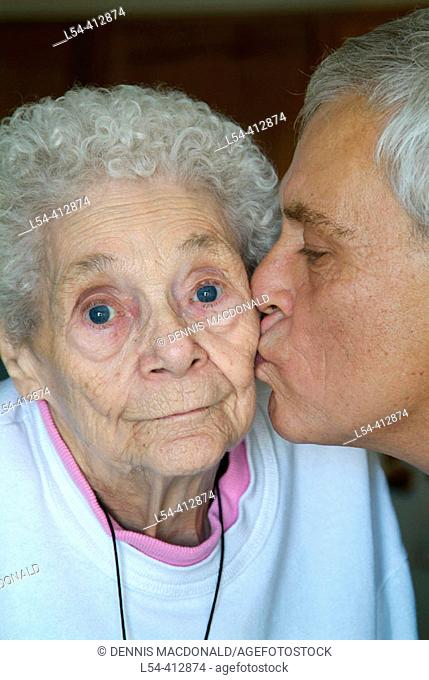 60 year old senior male kisses mother on the cheek on her 85 birthday