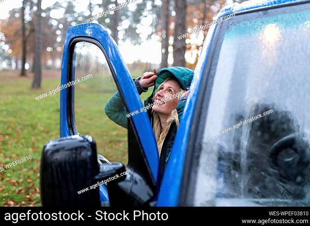 Smiling woman covering hair on rainy day at Cannock Chase