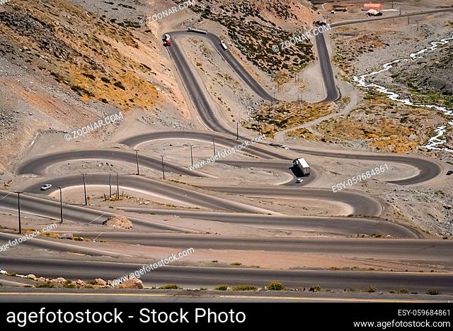 Cars trucks and lorries driving on the twisting and turning switchback road through high Andes in Chile, South America