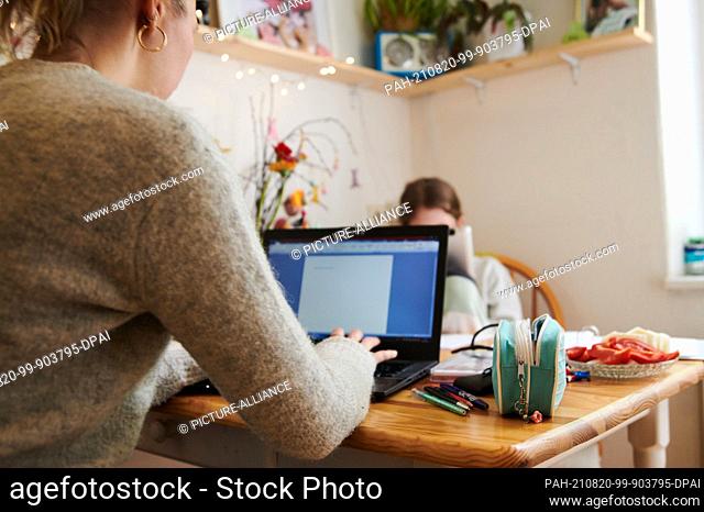 PRODUCTION - 29 April 2021, Berlin: A mother works at the kitchen table while her daughter looks into a tablet opposite. (to dpa ""Home office and new fears -...