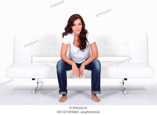 Casually dressed woman sitting on a white modern bed settee
