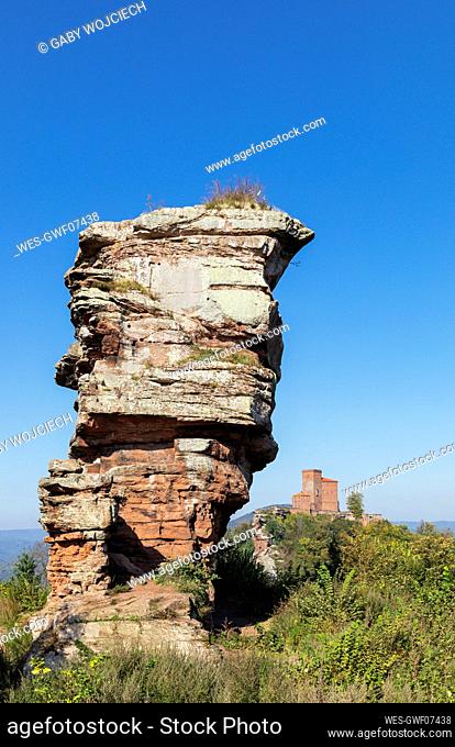 Germany, Rhineland-Palatinate, Sandstone rock formation in Palatinate Forest with Trifels Castle in distant background
