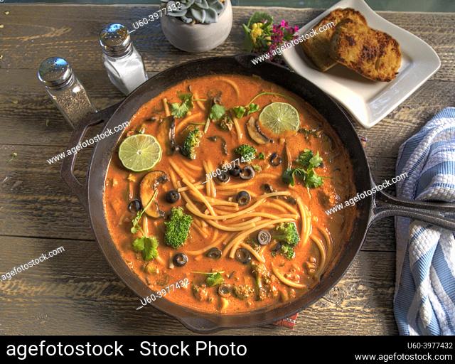 Top view of Red Thai Curry Noodle Soup on Natural Wood Table