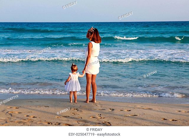 Happy mother holding her daughter on the beach