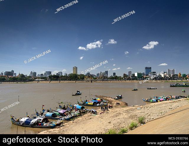 cham commmunity floating house boat village on tonle sap river with phnom penh city skyline in cambodia