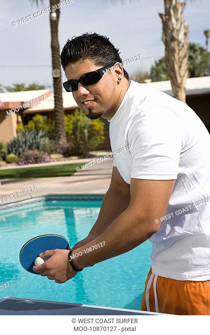 Young Man Playing Ping-Pong by Swimming Pool