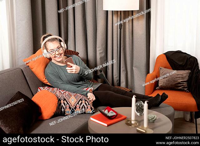 Smiling woman on sofa using cell phone