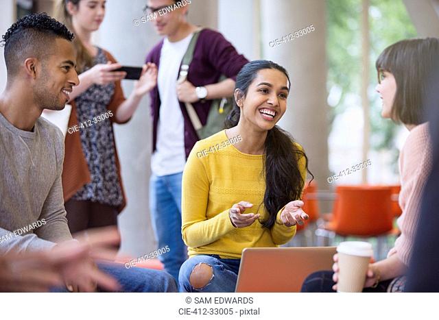 Smiling college students talking and drinking coffee in commons