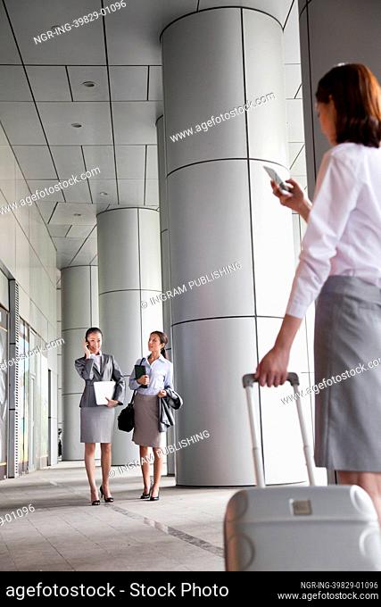 Three young businesswomen walking outside and talking on the phone