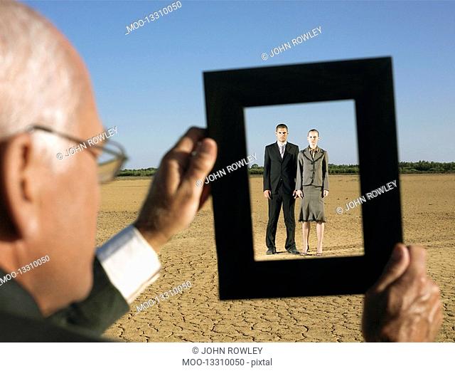Businessman framing couple in desert