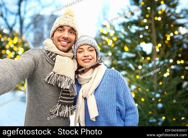 happy couple in winter clothes taking selfie