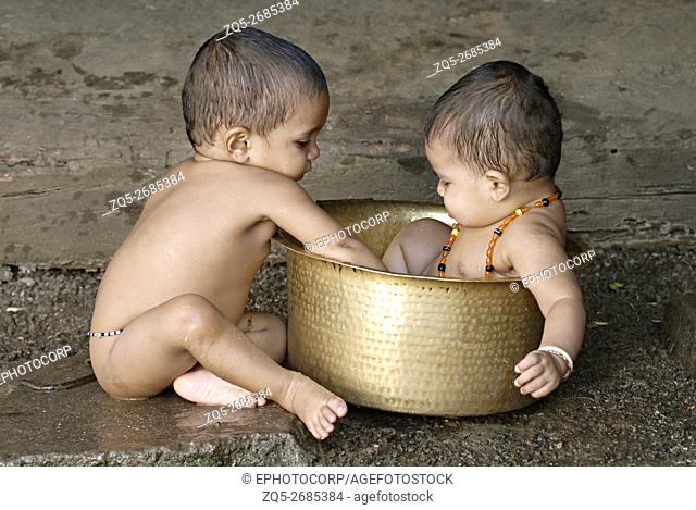 Warli babies bathing and playing in a vessel
