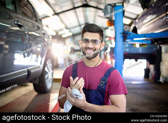 Portrait confident male mechanic wiping hands in auto repair shop