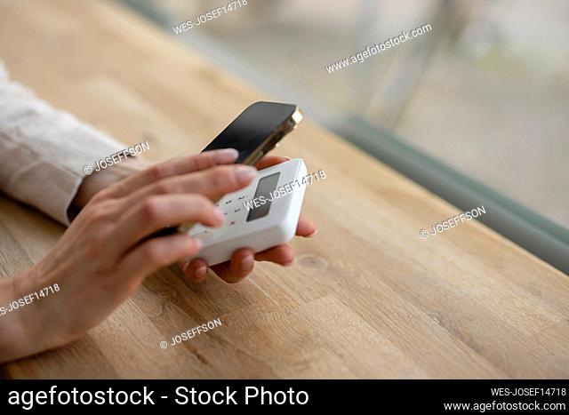 Hands of businesswoman scanning credit card reader through mobile phone on table