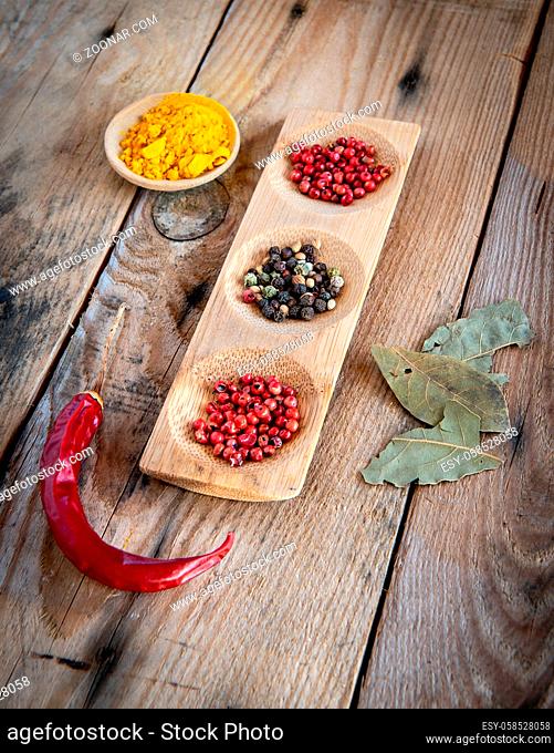 Collection of aromatic herbal peeper spices with red chilli peeper on the side, on a wooden surface