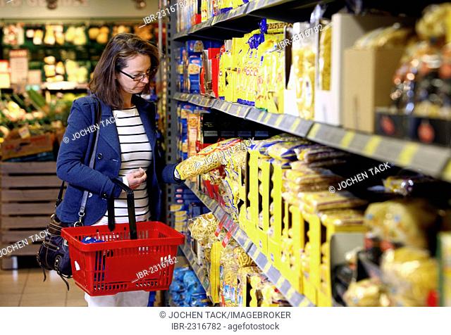 Woman purchasing noodles or pasta in a self-service grocery department, supermarket, Germany, Europe